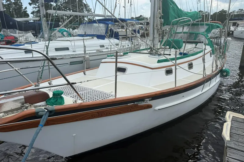 Slide: The Image of 1989 Cabo Rico 34 sailboat docked at marina, featuring classic design and green sail covers. - 3