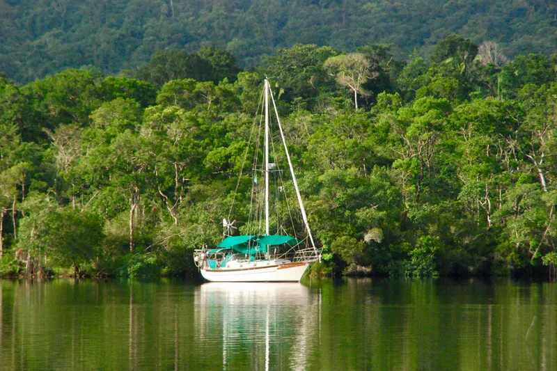 Slide: The Image of Sailboat Cabo Rico 34 (1989) anchored in lush, green forested waters. - 31