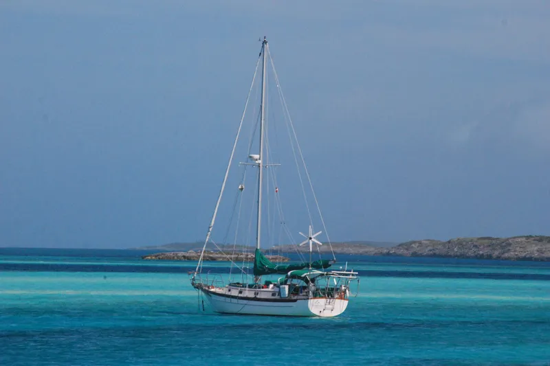 Slide: The Image of Sailboat Cabo Rico 34 (1989) anchored in clear turquoise waters, scenic coastal backdrop. - 35