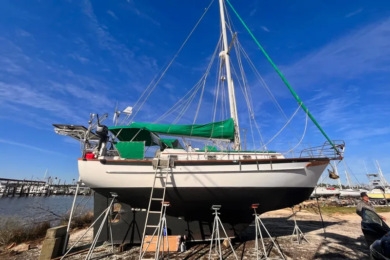 Slide: The Image of 1989 Cabo Rico 34 sailboat on stands, green canopy, clear blue sky background. - 4