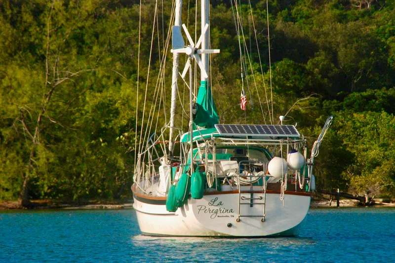 Slide: The Image of 1989 Cabo Rico 34 sailboat anchored in serene waters, surrounded by lush greenery. - 6