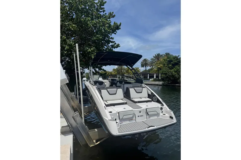 Slide: The Image of 2021 Yamaha Boats 252SD docked on a sunny day, surrounded by lush greenery. - 2