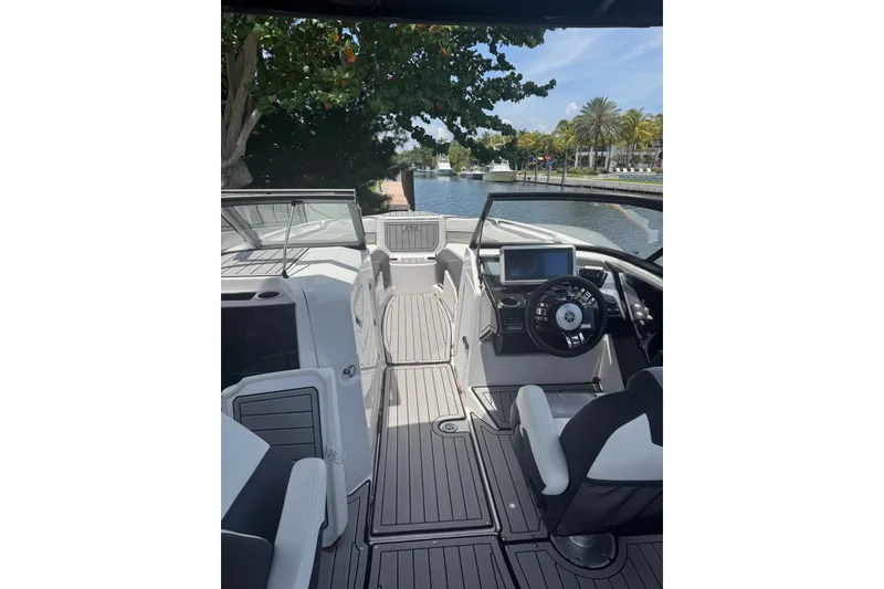 Slide: The Image of 2021 Yamaha Boats 252SD cockpit with modern steering and navigation system, docked by a scenic canal. - 3