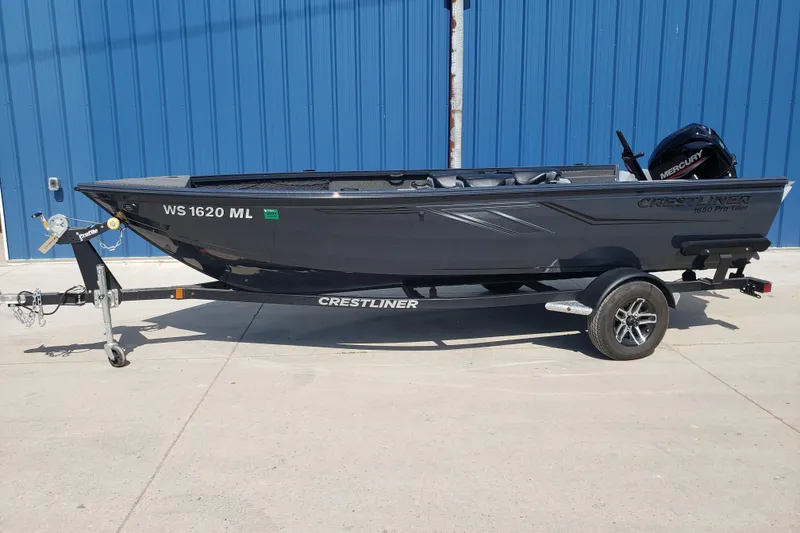 Slide: The Image of 2024 Crestliner 1650 Pro Tiller boat on trailer, parked by blue wall. - 1