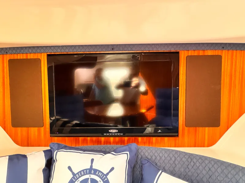 Slide: The Image of 2014 Pursuit OS 385 Offshore interior with TV and nautical-themed cushions. - 11