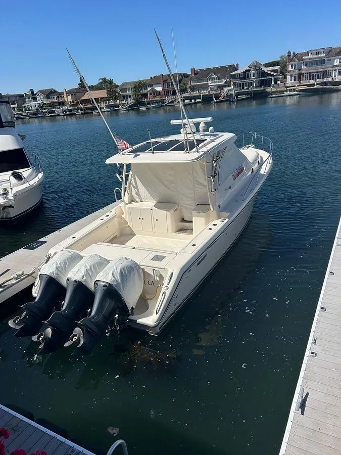 Slide: The Image of 2014 Pursuit OS 385 Offshore boat docked in a marina, featuring triple outboard engines. - 2