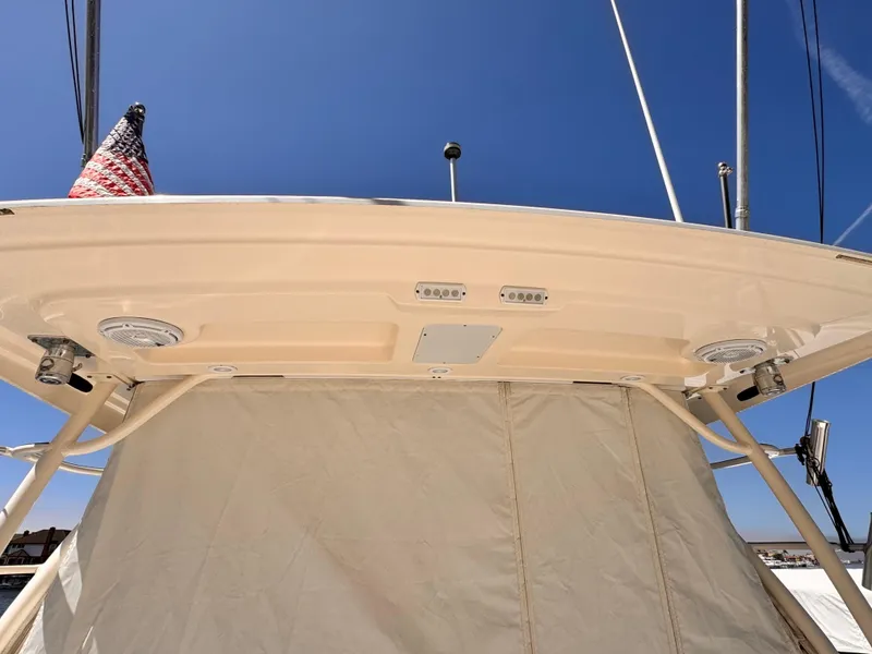 Slide: The Image of 2014 Pursuit OS 385 Offshore boat canopy with speakers and American flag against blue sky. - 22