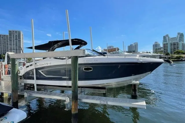 Slide: The Image of 2014 Chaparral 307 SSX boat docked in a marina with city skyline background. - 1