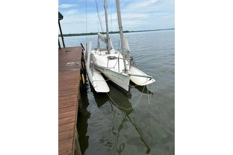 Slide: The Image of Corsair F24 MKI 1994 trimaran docked on calm water, clear sky background. - 7