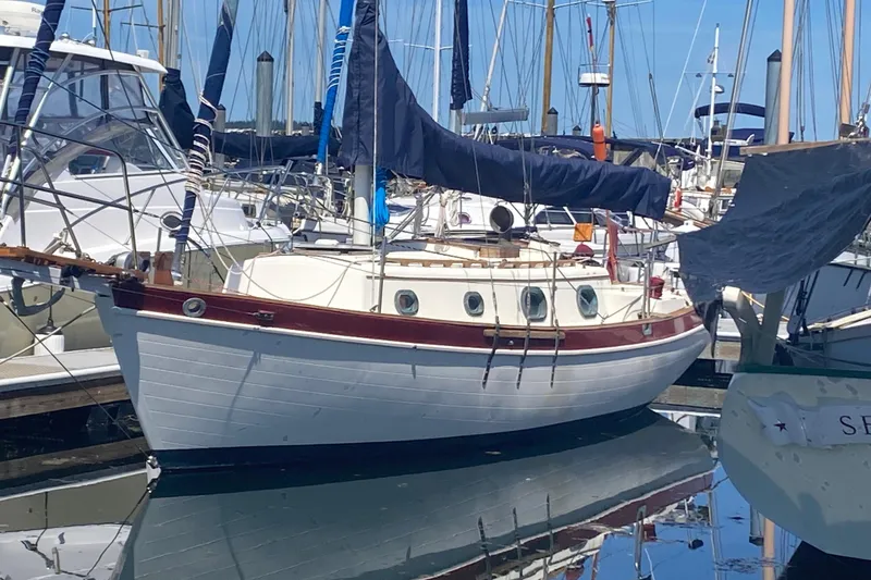 The Image of 1980 Pacific Seacraft Orion 27 sailboat docked in a marina, reflecting on water. - 1