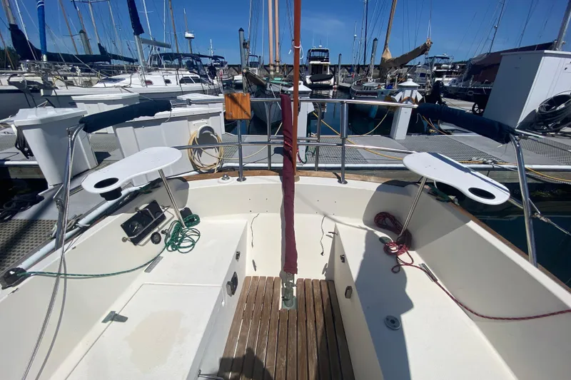 Slide: The Image of 1980 Pacific Seacraft Orion 27 sailboat cockpit at marina, featuring wooden deck and nautical equipment. - 10