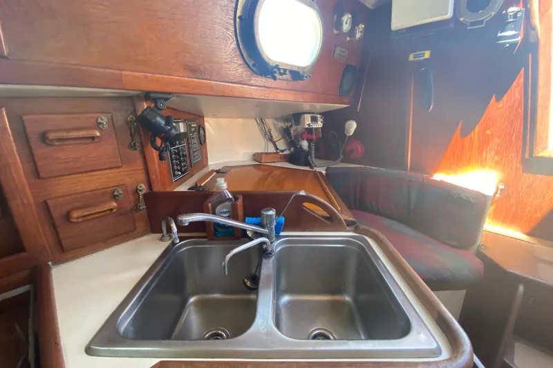 Slide: The Image of Interior of 1980 Pacific Seacraft Orion 27 sailboat, featuring a compact kitchen area. - 15