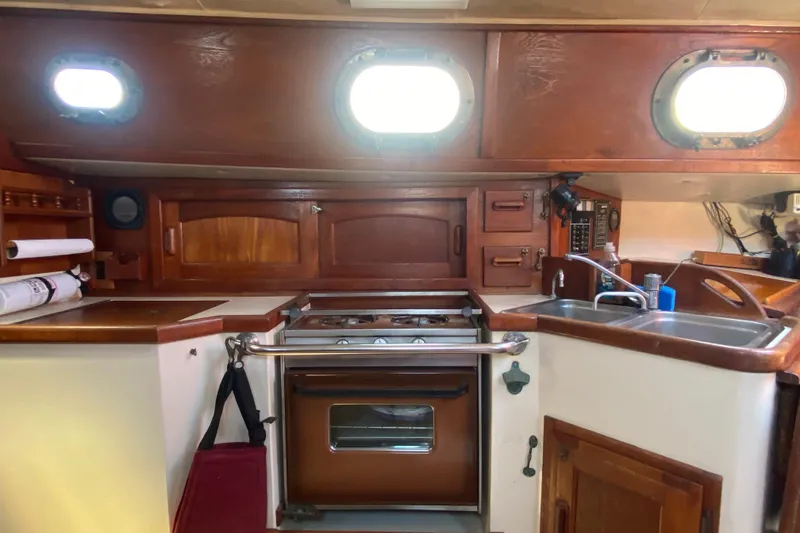 Slide: The Image of Interior of 1980 Pacific Seacraft Orion 27 sailboat kitchen with wooden cabinetry and stove. - 16
