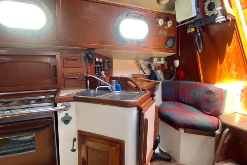 Slide: The Image of Cozy 1980 Pacific Seacraft Orion 27 yacht interior with kitchen and seating area. - 17