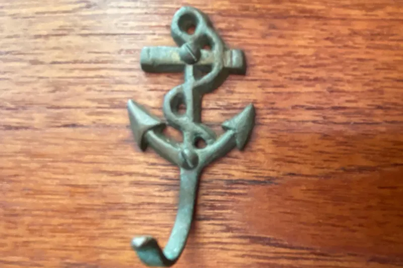 Slide: The Image of Bronze anchor hook on wooden surface, Pacific Seacraft Orion 27, 1980. - 22