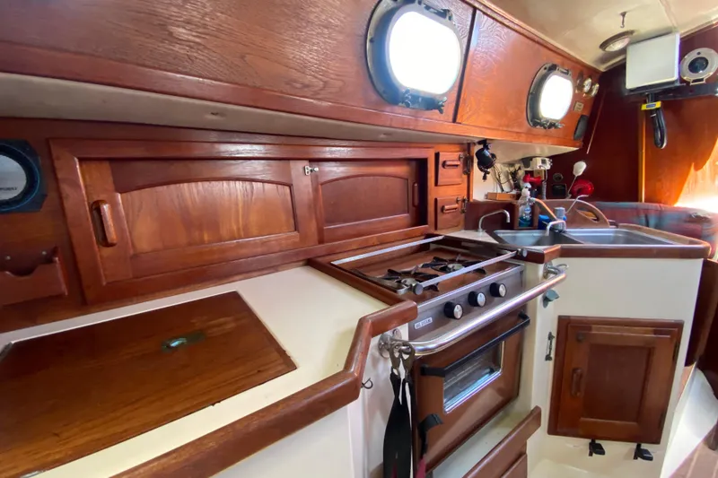 Slide: The Image of Interior of 1980 Pacific Seacraft Orion 27 sailboat galley with wood cabinetry and stove. - 24