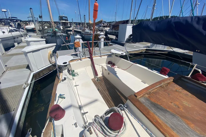 Slide: The Image of 1980 Pacific Seacraft Orion 27 sailboat docked at marina, showcasing open cockpit and deck. - 9