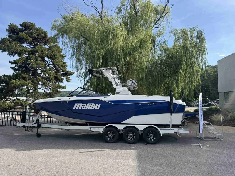 The Image of 2025 Malibu M242 boat on trailer, surrounded by trees. - 1