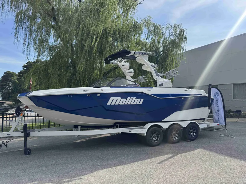 Slide: The Image of 2025 Malibu M242 boat on trailer, blue and white design. - 8