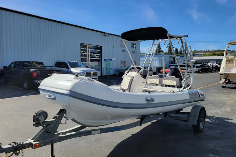 The Image of 2022 Highfield Sport 460 boat on trailer, parked outside a warehouse under clear blue sky. - 0