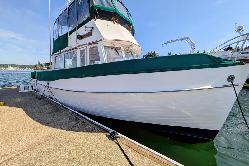 The Image of 1979 Grand Banks 42 Classic yacht docked, featuring green canvas covers and white hull. - 0