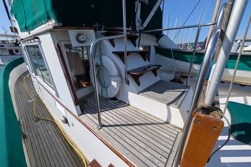 Slide: The Image of 1979 Grand Banks 42 Classic yacht deck with wooden stairs and green canopy. - 17