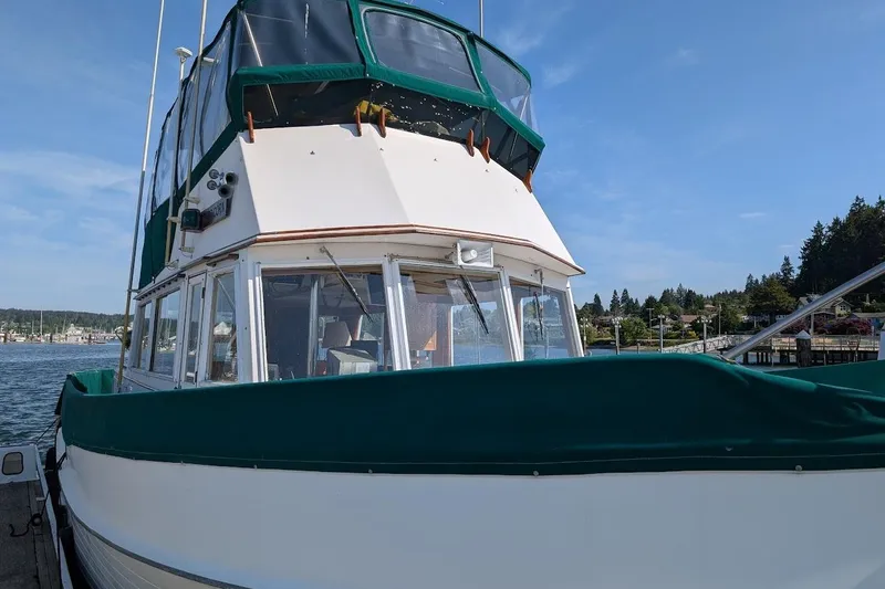 Slide: The Image of 1979 Grand Banks 42 Classic boat docked, featuring green canvas cover and clear blue sky. - 2