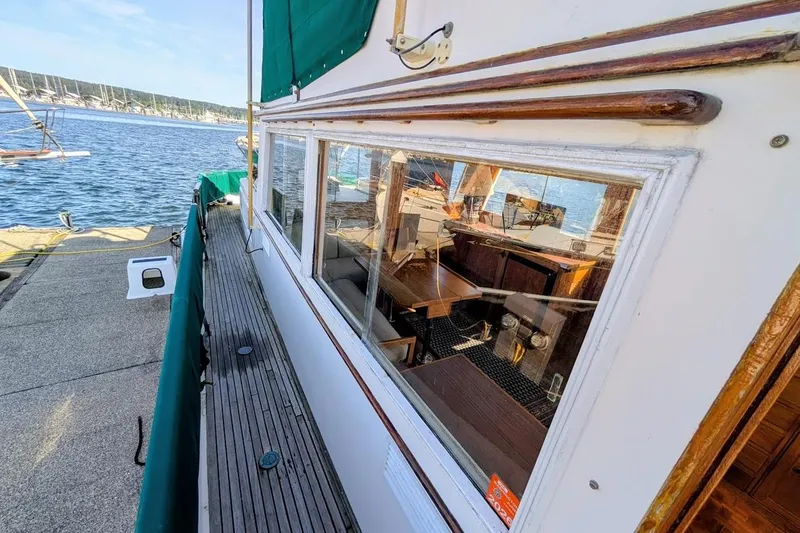 Slide: The Image of 1979 Grand Banks 42 Classic yacht docked, showcasing wooden deck and interior through window. - 22