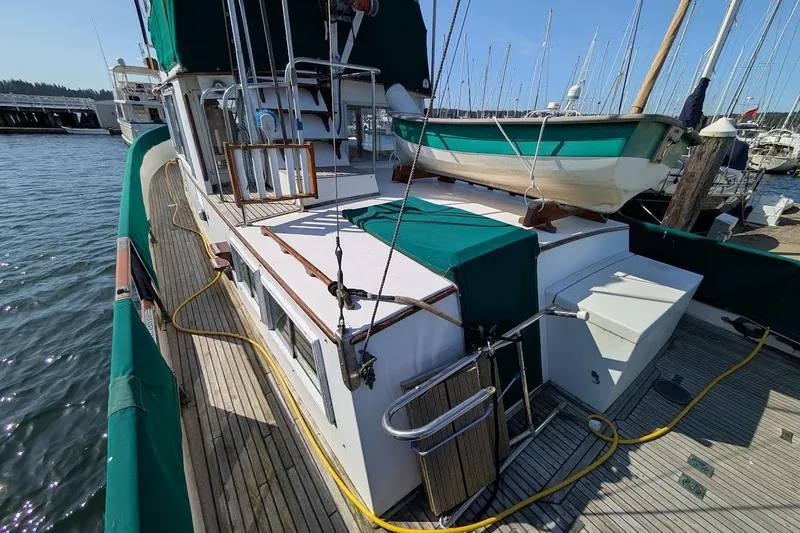 Slide: The Image of 1979 Grand Banks 42 Classic yacht docked, featuring green covers and a small boat on deck. - 23