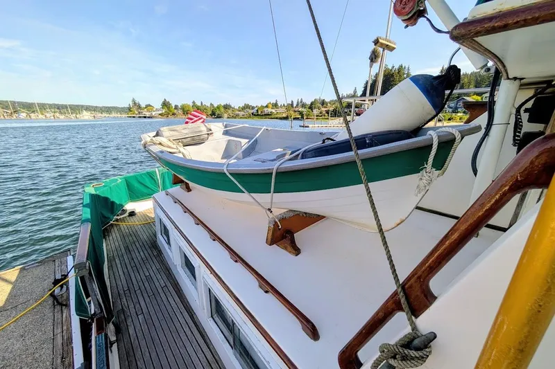 Slide: The Image of 1979 Grand Banks 42 Classic yacht with a small boat on deck, docked by the water. - 25