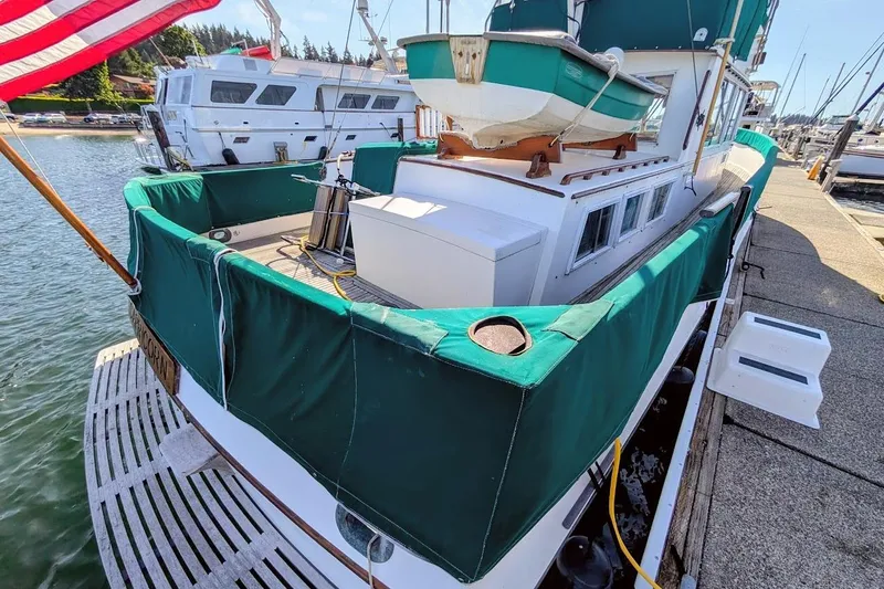Slide: The Image of 1979 Grand Banks 42 Classic yacht docked, featuring green canvas covers and American flag. - 4