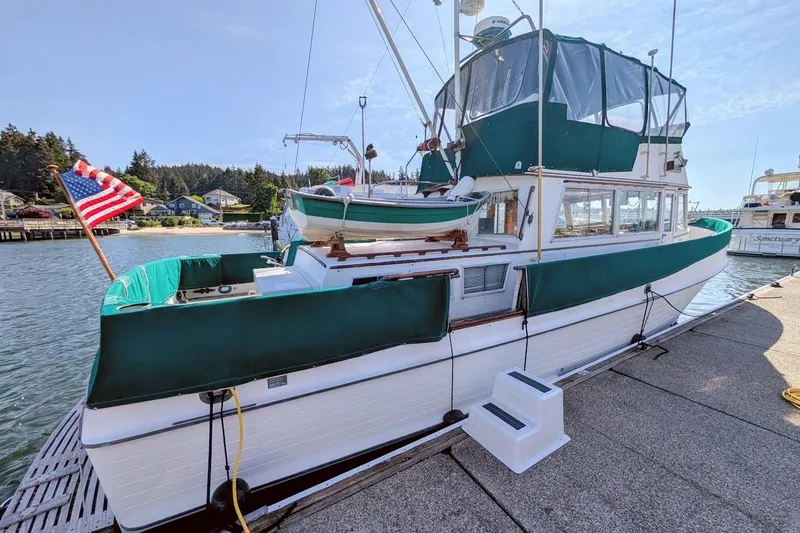 Slide: The Image of 1979 Grand Banks 42 Classic yacht docked, featuring green canvas covers and American flag. - 5