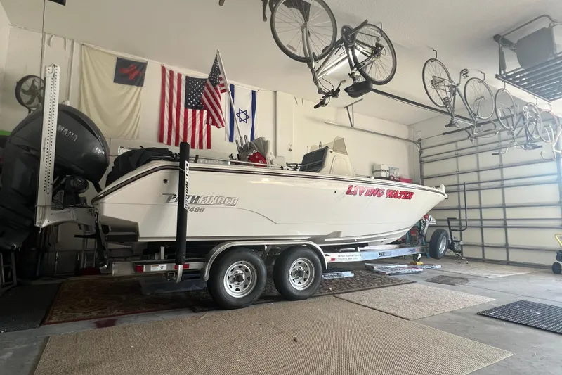 The Image of 2024 Pathfinder 2400 Open boat in garage with flags and bicycles overhead. - 1