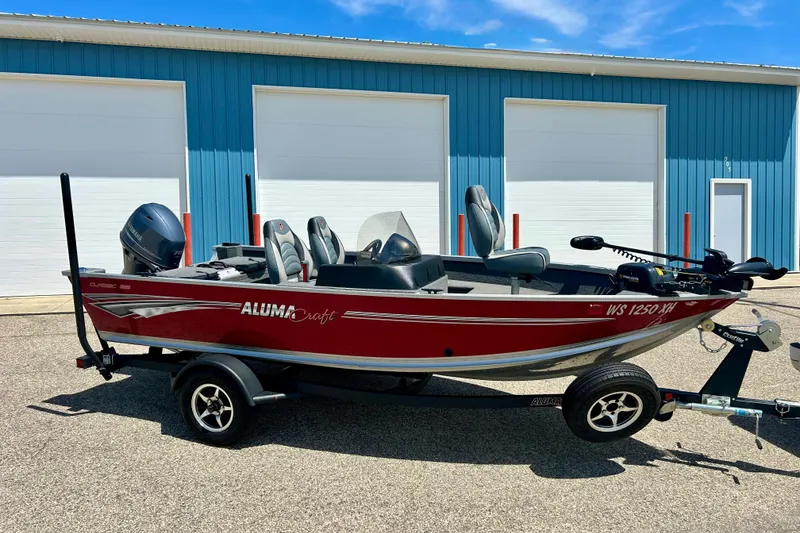 The Image of 2019 Alumacraft Classic 165 Sport boat in red, parked outside a blue building. - 0