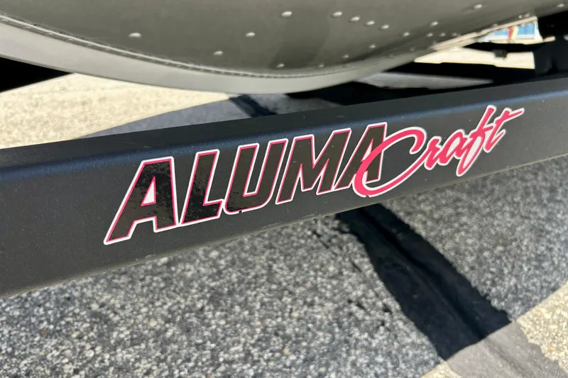 Slide: The Image of 2019 Alumacraft Classic 165 Sport boat trailer with logo on pavement. - 23