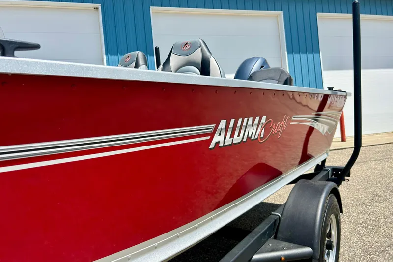 Slide: The Image of 2019 Alumacraft Classic 165 Sport boat in vibrant red, parked on a trailer. - 6