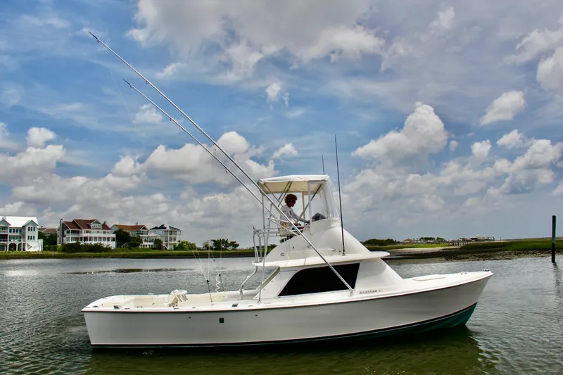 The Image of 1970 Bertram 31 Sportfisher boat on calm water under a cloudy sky. - 0
