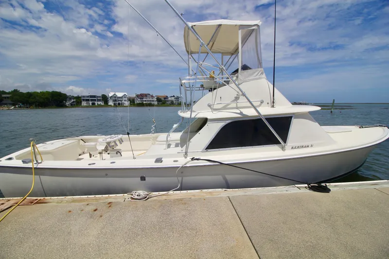 Slide: The Image of 1970 Bertram 31 Sportfisher docked by the waterfront under a clear blue sky. - 2