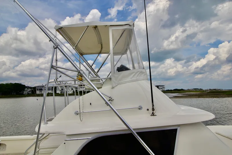 Slide: The Image of 1970 Bertram 31 Sportfisher boat with canopy, docked under a cloudy sky. - 32