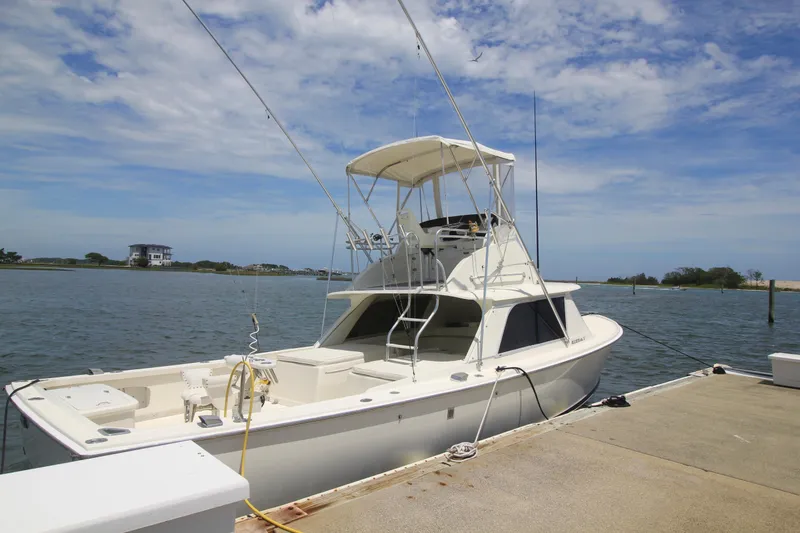 Slide: The Image of 1970 Bertram 31 Sportfisher boat docked by the water under a clear blue sky. - 5