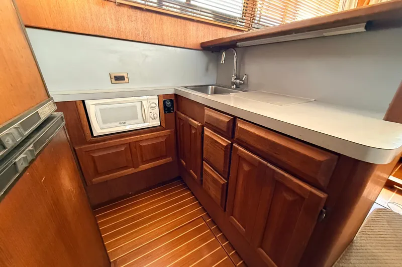 Slide: The Image of 1986 Viking 35 Convertible yacht kitchen with wood cabinets, sink, and microwave. - 12