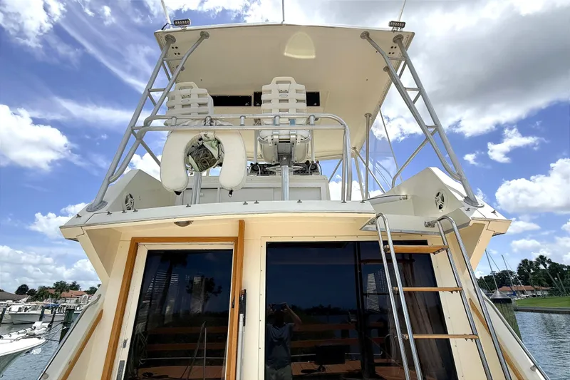 Slide: The Image of 1986 Viking 35 Convertible yacht with flybridge, docked under a partly cloudy sky. - 5