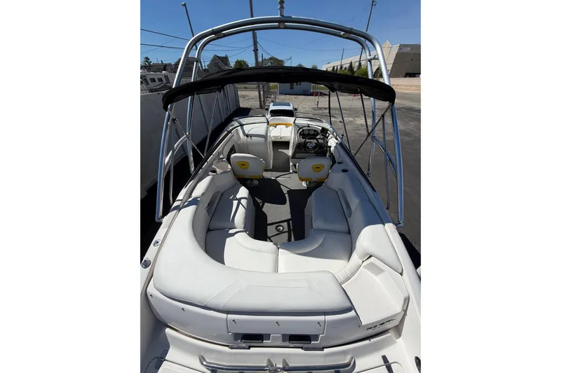 Slide: The Image of 2007 Regal 2400 Bowrider boat with white seating and black canopy in a parking area. - 10