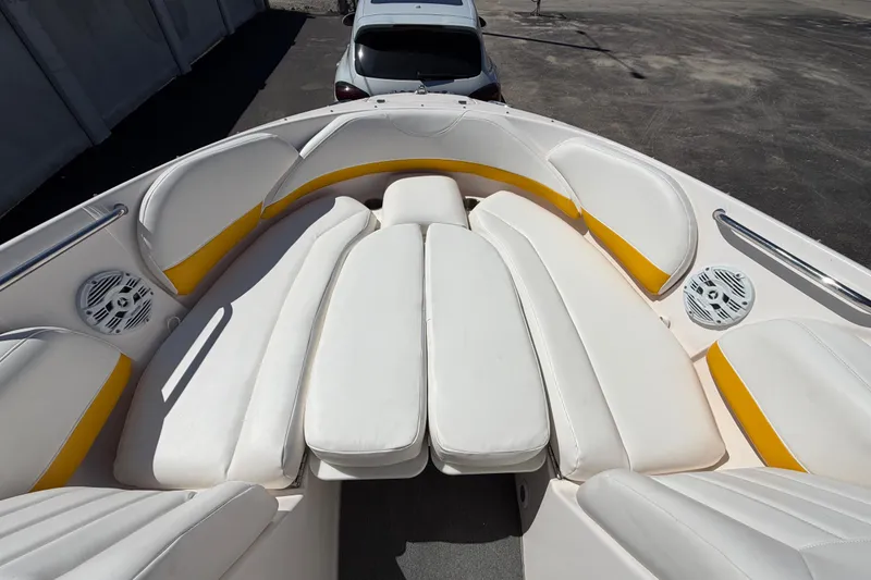 Slide: The Image of 2007 Regal 2400 Bowrider boat interior with white and yellow seating, parked on pavement. - 14