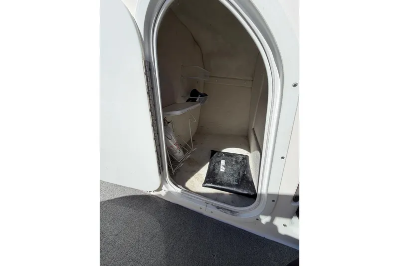 Slide: The Image of Interior storage compartment of a 2007 Regal 2400 Bowrider boat, showing open door and accessories. - 16