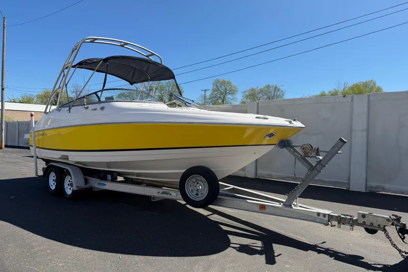 Slide: The Image of 2007 Regal 2400 Bowrider boat with yellow hull on trailer, parked outdoors. - 2