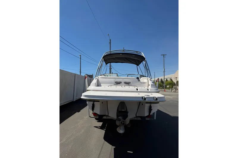 Slide: The Image of 2007 Regal 2400 Bowrider boat, rear view, parked outdoors under clear blue sky. - 4
