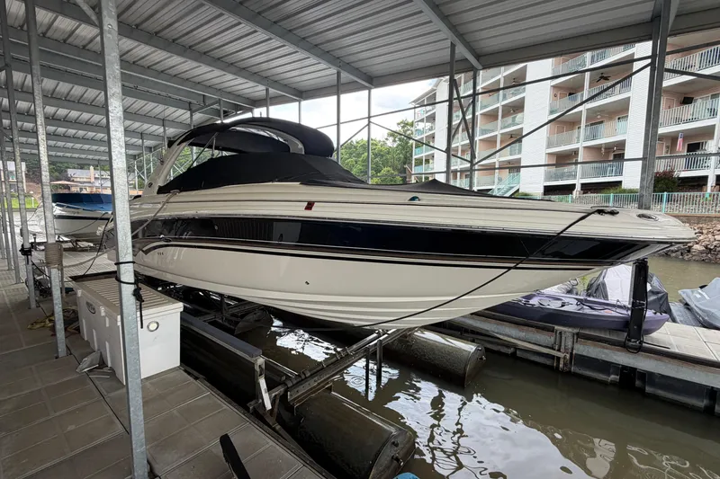 The Image of 2003 Sea Ray 290 Bowrider docked under a covered marina with nearby buildings. - 0