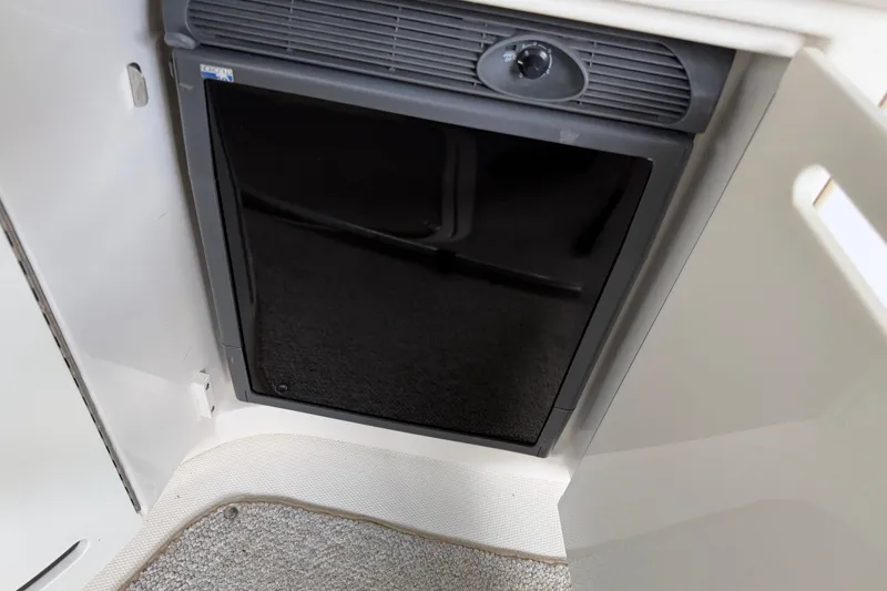 Slide: The Image of 2003 Sea Ray 290 Bowrider interior fridge with black door and control knob. - 14