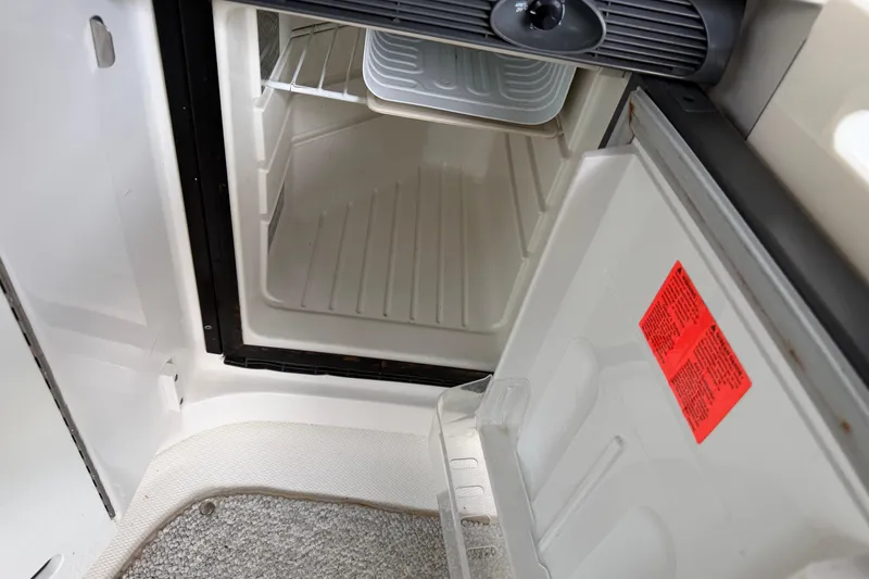 Slide: The Image of Open refrigerator inside a 2003 Sea Ray 290 Bowrider boat, showing interior shelves. - 15
